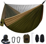 Camping hammock with mosquito net fully assembled and hanging between two trees